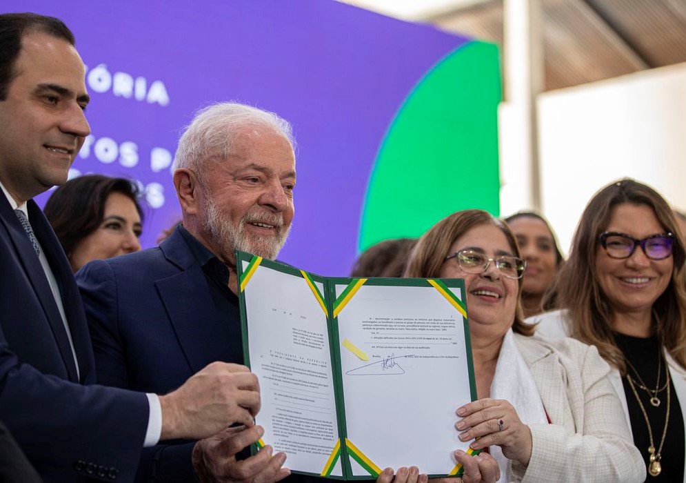 Lula mostra a nova lei e reforça que as pessoas podem encaminhar os casos por meio de um portal do Ministério do Trabalho ou pelo telefone: Disque 100, Disque 180 ou Disque 158