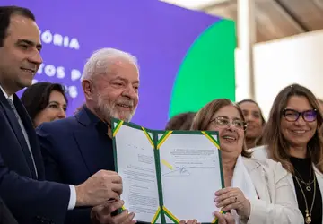 Lula mostra a nova lei e reforça que as pessoas podem encaminhar os casos por meio de um portal do Ministério do Trabalho ou pelo telefone: Disque 100, Disque 180 ou Disque 158